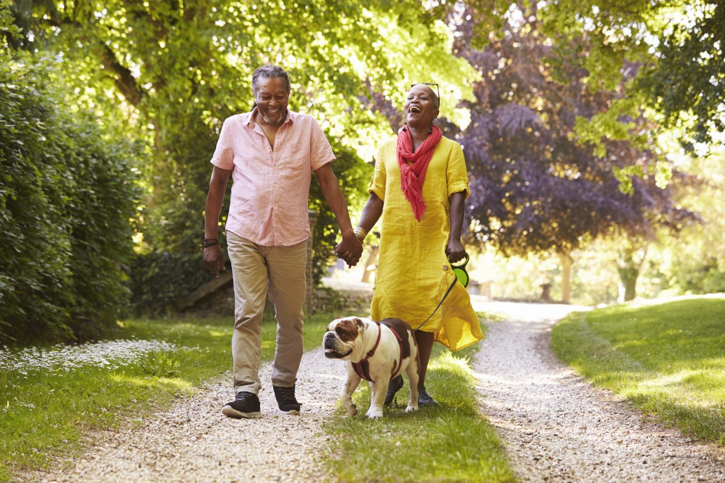 Couple walking a dog and laughing