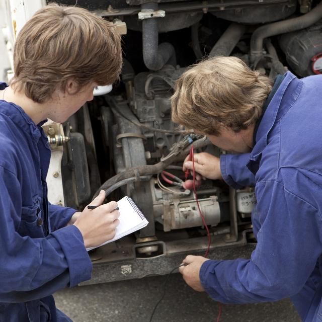 Two mechanics in front of a vehicle