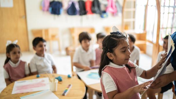 Young children in class, schoolgirl gives presentation.