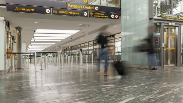 Border control at UK airport with blurred figures walking past